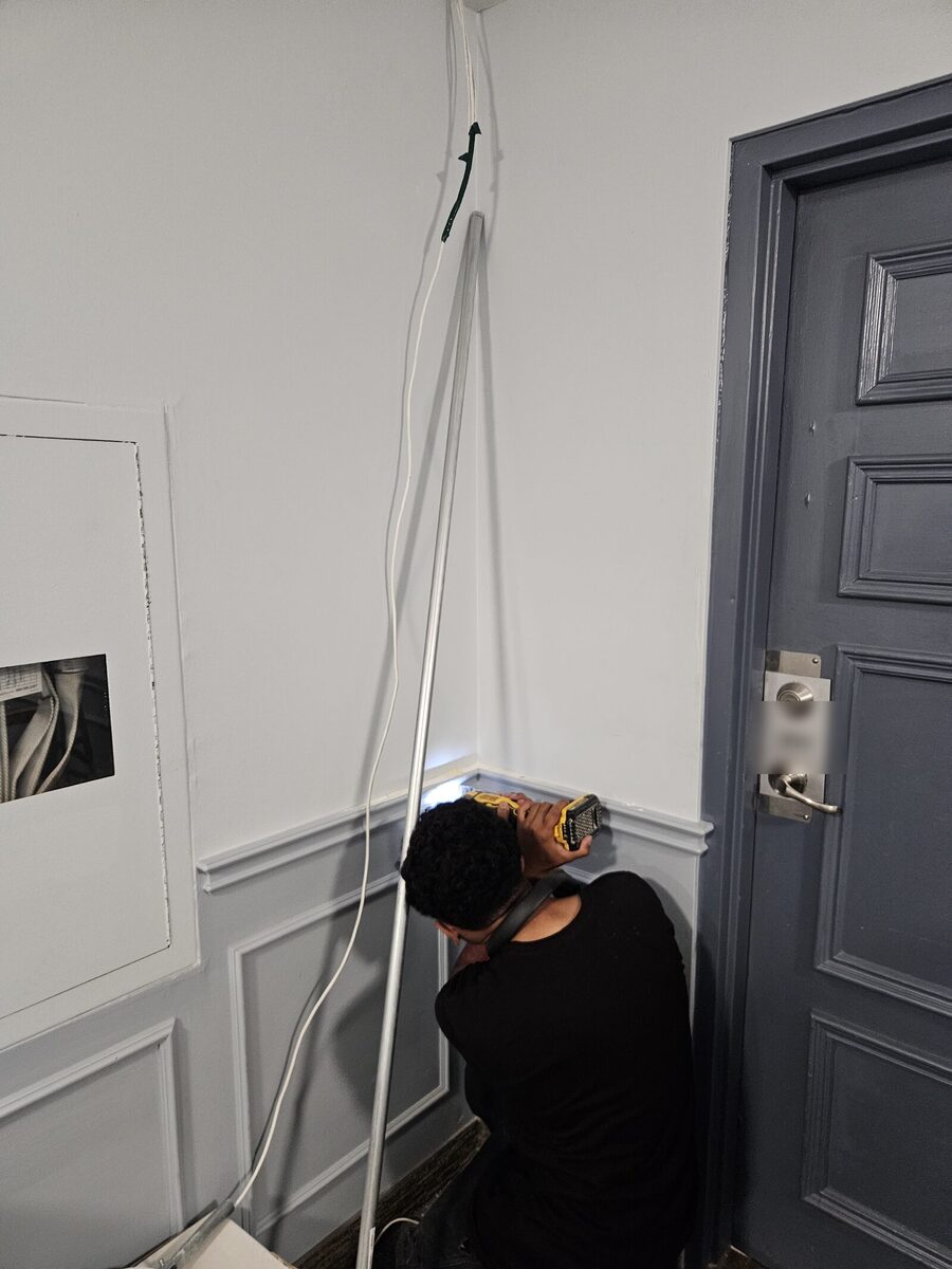 Technician pulling Cat6 cable through an upper-floor corridor of an occupied apartment building in London, Ontario.