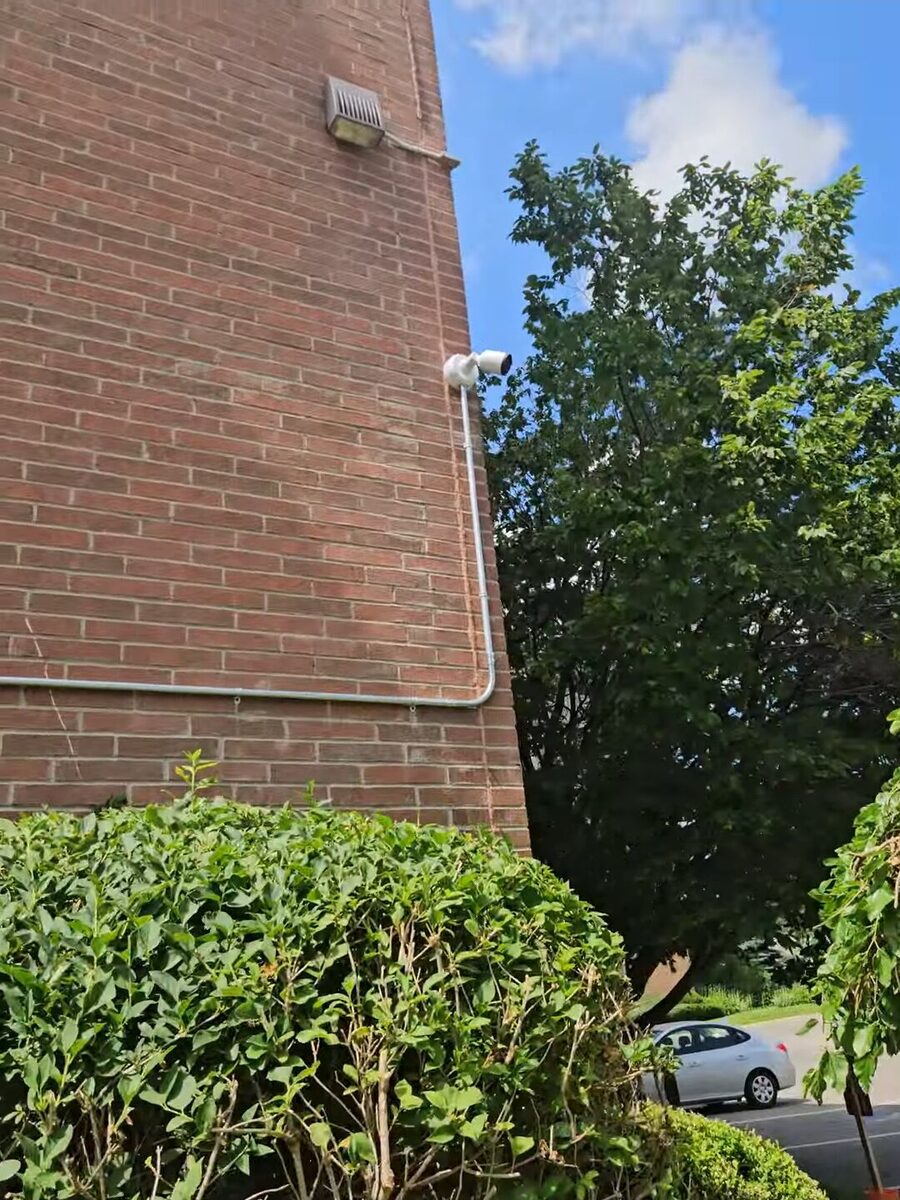 UniFi G6 Pro Bullet camera mounted on the exterior brick wall of an apartment building overlooking the parking lot in London, Ontario.