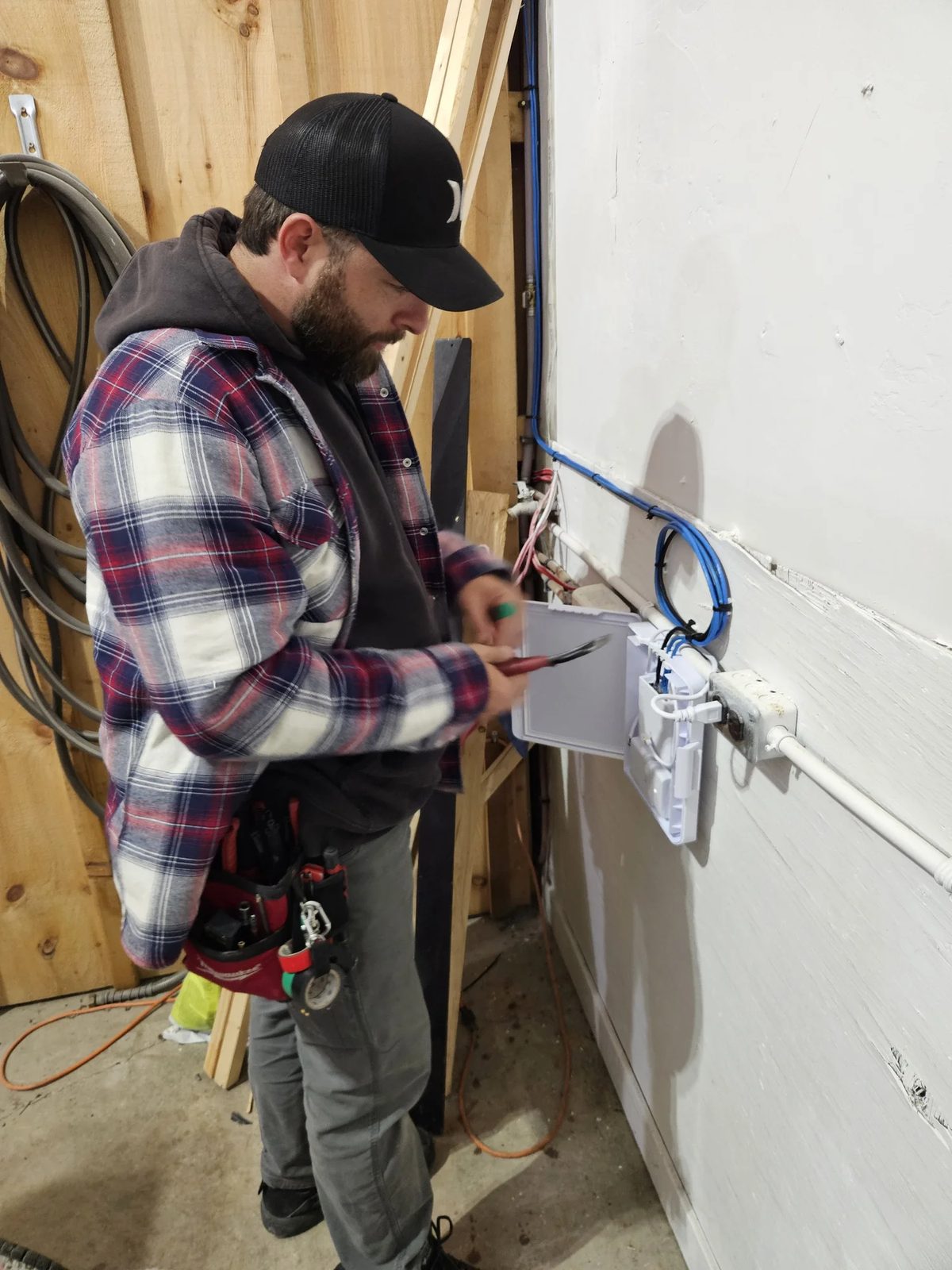 Kyle terminating cables in a UniFi Flex utility box at a remote building on a construction site
