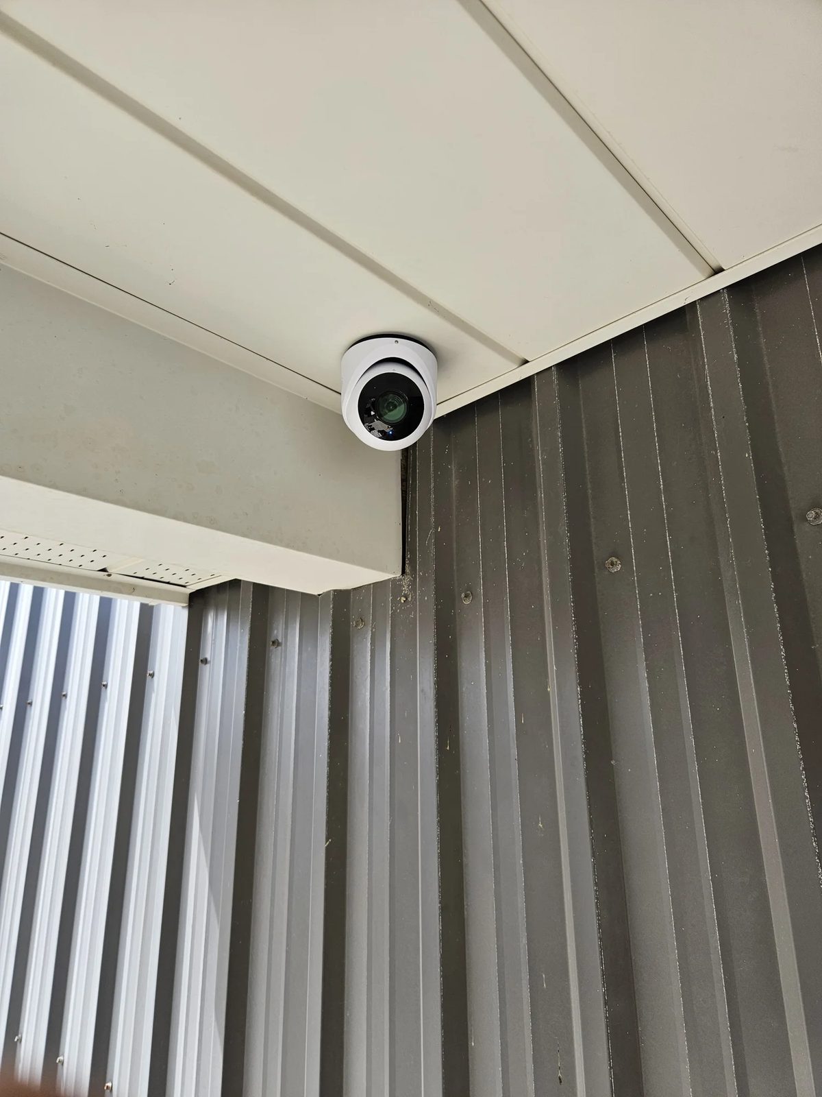 UniFi G6 Turret 4K camera mounted in the corner of a steel building covering an entrance