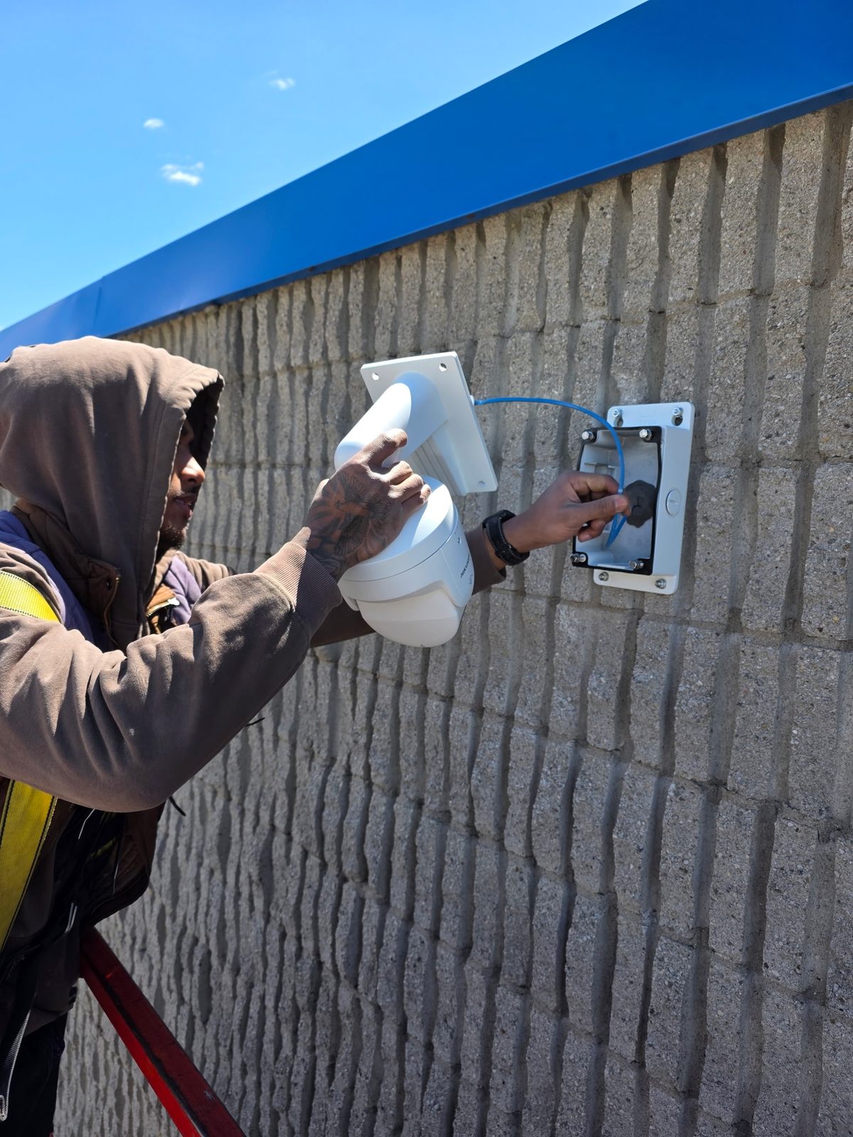 Hikvision panoramic camera wired into a weatherproof junction box on a perimeter wall