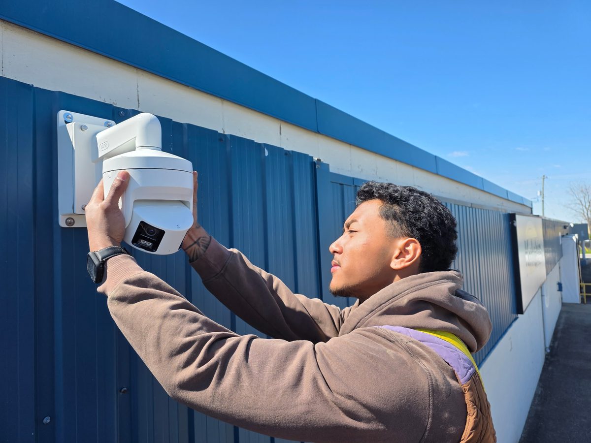 London Tech Solutions technician installing a Hikvision panoramic active-deterrence camera at a South London Ontario manufacturing facility