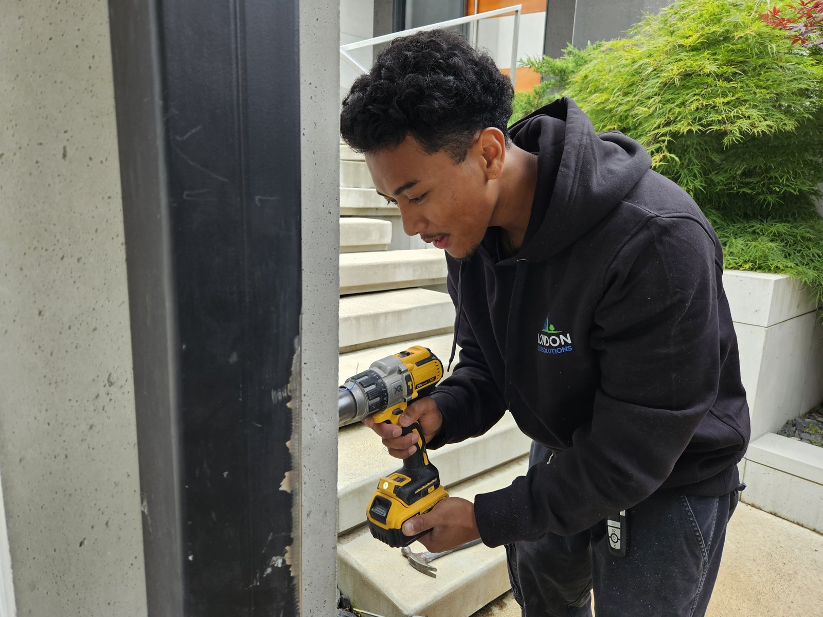 London Tech Solutions technician mounting access control hardware into a custom steel-and-concrete entry gate in Sarnia, Ontario